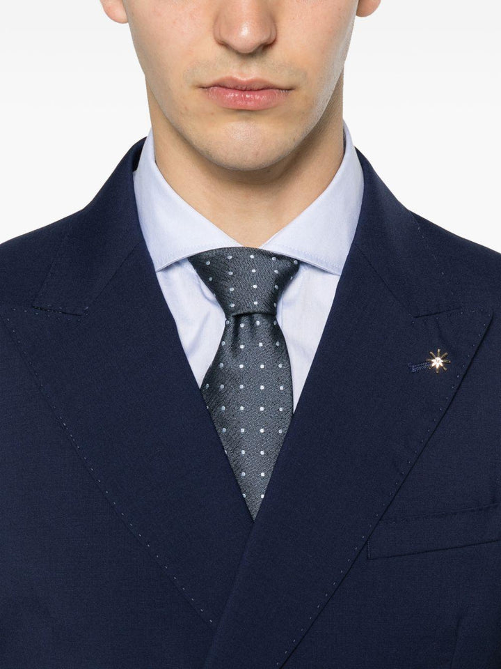 Abito blu doppiopetto con spilla sul revers 
